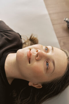 Girl lying on a surface with eyes looking up in a room