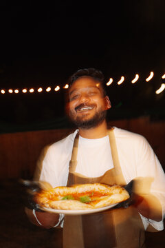 Chef Holds Fresh Pizza at Night During Outdoor Event