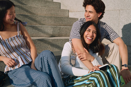 Three friends relaxing together on sunny city steps