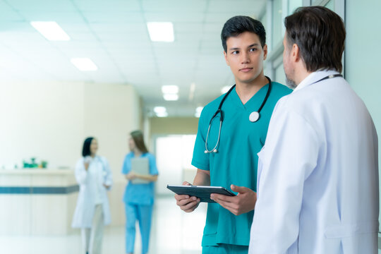 Professional healthcare workers discussing patient information in a modern hospital hallway highlighting teamwork communication medical excellence and quality patient care with generous copy space.
