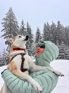 Happy woman holding her dog during a winter adventure in the Austrian 