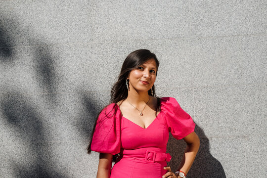 Smiling Indian woman against grey wall background.
