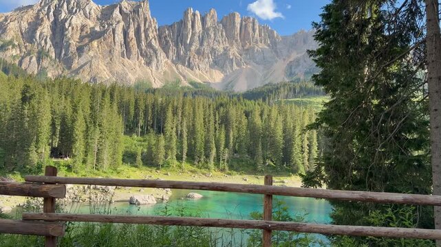 Lake Carezza Panoramic View with Wooden Fence, Turquoise Water Beneath Rugged Dolomite Peaks South Tyrol Italy