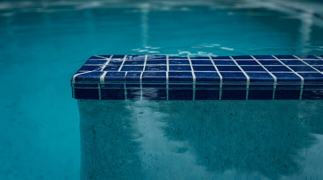 Blue mosaic tiled swimming pool step nosing | Modern pool design with turquoise water | Close up of pool edge tiles underwater | Luxury backyard pool renovation details