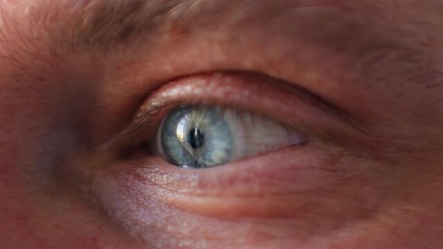 Extreme Close Up Male blue Eye Blinking And Looking Around In Dark, middle aged portrait
