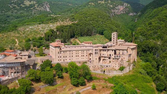 Santa Scolastica Monastery Subiaco Italy Aerial Drone Pullback Dolly Zoom Flight Between Mountains Revealing Deep Aniene Gorge Ravine Medieval Benedictine Abbey Lazio Travel Video 4K UHD