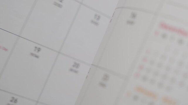 flipping through planner pages in close up revealing monthly calendar layout and schedule organization