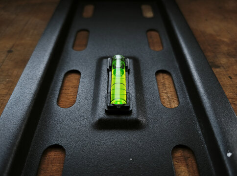 Close-up of a green bubble level on a black metal mounting bracket.