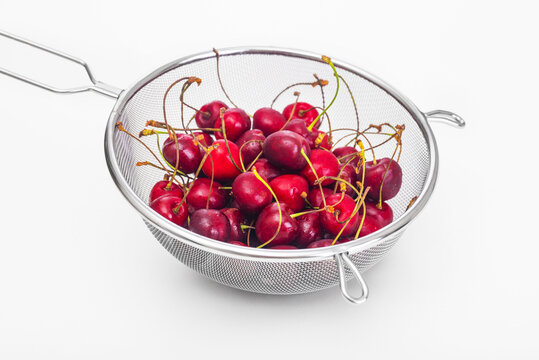 Ripe cherries in a colander on a white background