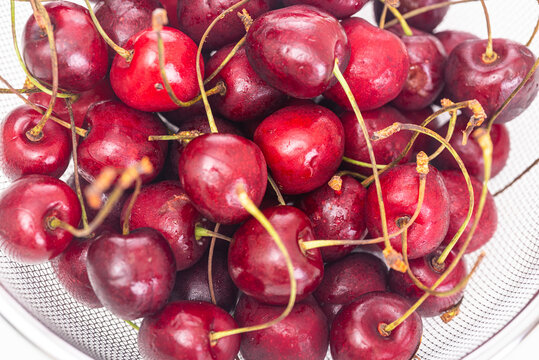 Ripe cherries in a colander close up on a white background