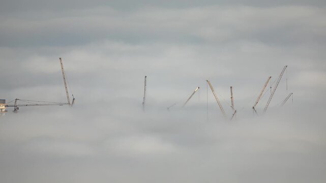 mist of clouds below the skyline of dubai with only construction cranes showing