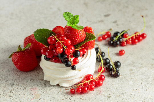 Pavlova dessert with strawberries, black currant, red currant, and mint.