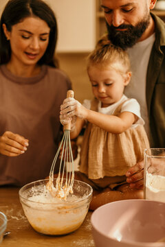Family baking together in kitchen, child learning new skills