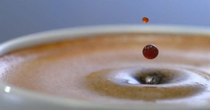 Espresso coffee drop creating a splash and ripple in crema, super slow motion