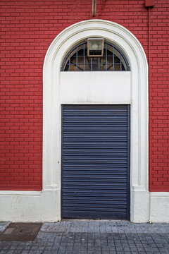 Closed metal shutter door on red brick building facade.