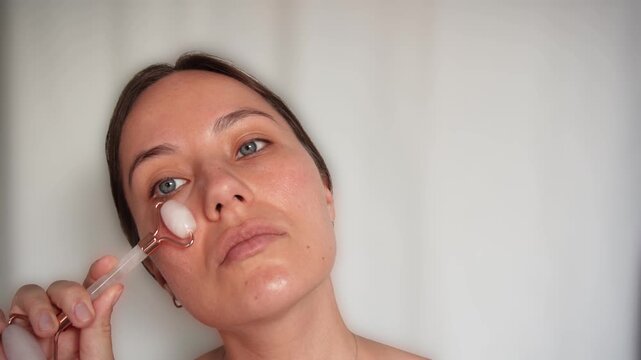 Woman Using Pink Jade Facial Roller for Skincare Massage Routine on White Background, Beauty Wellness and Self Care Concept