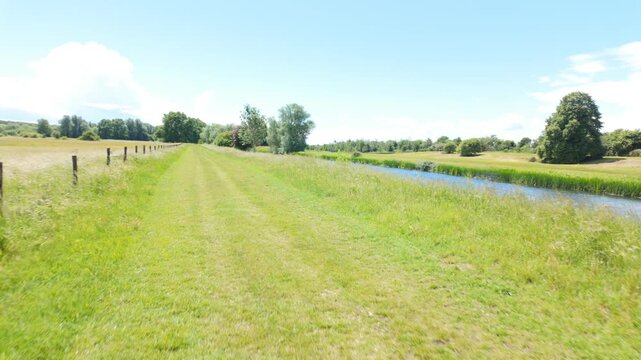 Ferry Meadows Country Park, Peterborough, Cambridgeshire, England, UK - June 09 2026: PoV, gimbal, Walking sequence - beside the river nene on a windy and bright summers afternoon