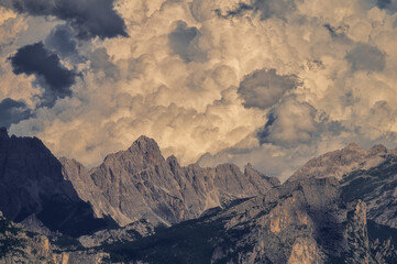 Dramatic landscape of jagged mountain peaks under a heavy, textured cloudy sky. Ideal for nature backgrounds and cinematic themes. © marcodenaro