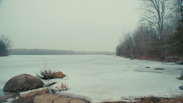 Winter Serenity: Frozen Lake, Bare Trees, Rocky Shores