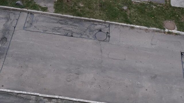 High angle top-down view of a completed pothole road repair with a sealed rectangular patch on the asphalt road surface.
