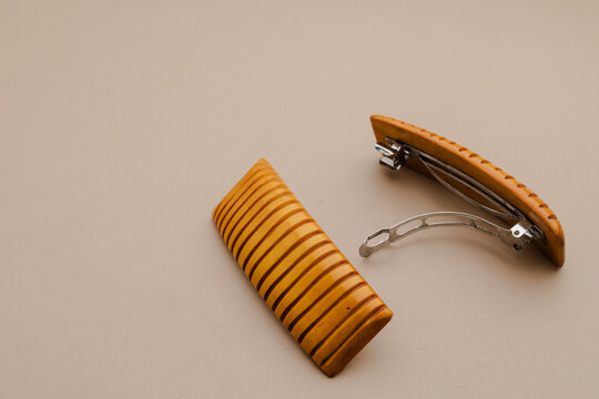 Two elegant rectangular hair barrettes with carved stripes and metal clips, showcasing a natural wood tone against a light neutral background