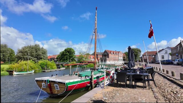 Ribe, Denmark &ndash; Historic waterfront promenade with sailing boat, a restaurant terrace and a summer harbor atmosphere