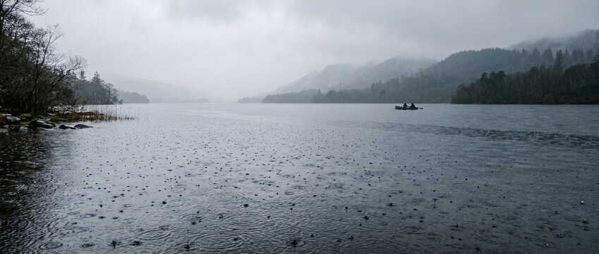 Paysage de lac sauvage sous une pluie battante et une brume mystique entour&eacute; de montagnes