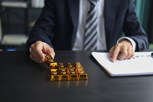 Gold investment Concept. Businessman working on financial planning and gold investment analysis with bullion on desk.