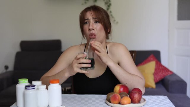 Woman struggles to drink a trendy healthy shake and almost gags proving that fashionable wellness products and functional nutrition are not always pleasant to consume