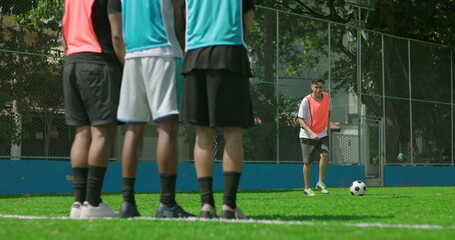 Obraz premium Casual soccer game among friends on local field, player steps up for free kick as teammates form wall, emphasising teamwork, community, and recreational fun