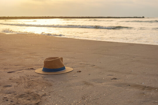 Panama hat on sandy beach with footprint by the sea