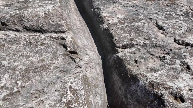 Naxxar, Malta 06.07.2026 - - Salina cart ruts: Two children walk along ancient rock-cut ruts on limestone terrain near residential buildings in Naxxar, Malta. The mysterious grooves, believed to date 