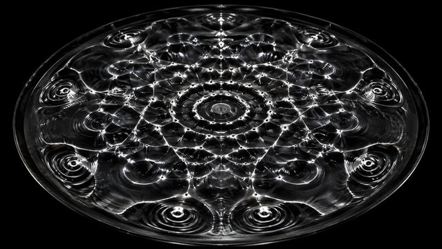 Cymatics water vibration standing wave pattern on dark plate showing perfectly symmetrical mandala-like node rings overhead macro physics
