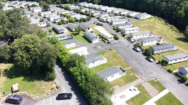 Aerial drone 4K clip showing caravans placed within valley vegetation under bright daylight Wales