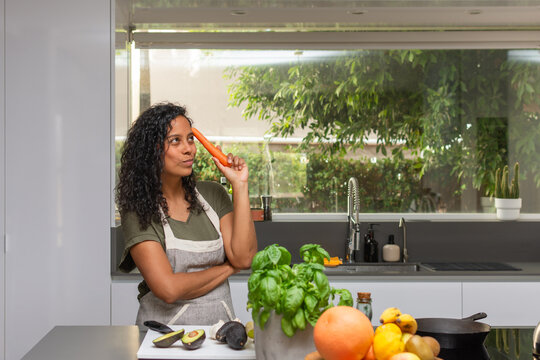 Woman thinking with carrot while looking toward copy space