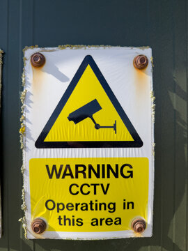 Yellow warning surveillance camera wall sign close up