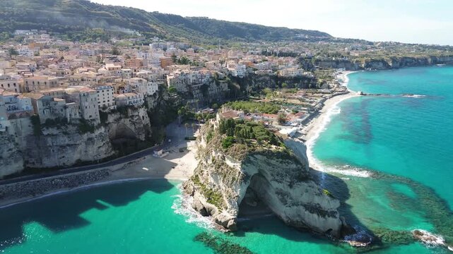 Tropea, Calabria, Italy. Forward aerial drone approach to Santa Maria dell&rsquo;Isola, revealing the cliffside old town, sandy beaches and turquoise Tyrrhenian Sea along the Costa degli Dei.