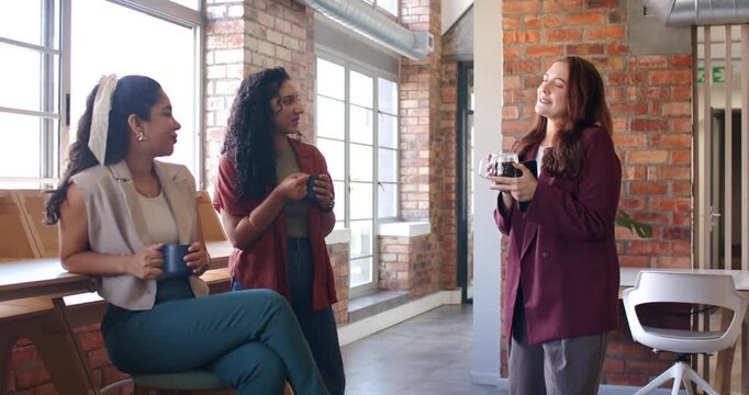 Three women in blazers at lounge, speaker gesturing with carafe making peers sipping mugs on break