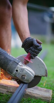 Person wearing safety glove operating angle grinder cutting metal creating bright sparks