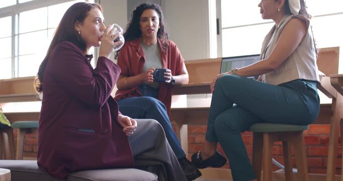 Diverse women team sitting at cafe bar, left sipping mug leading center woman speaking near laptop