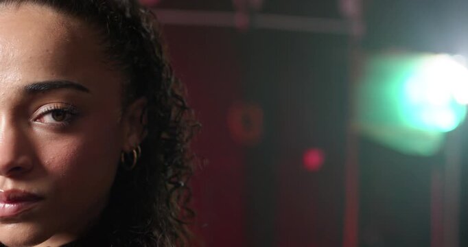 Tight African-American woman posing in studio for promo holding gaze blinking green flare shifting
