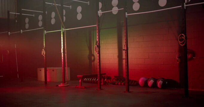 Colored lights are shifting, bathing rig with bench, dumbbells, med balls in gym for training vibe