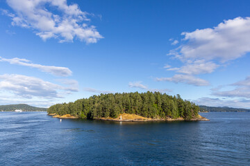 Fototapeta premium Forest-Covered Island and Calm Sea Under Blue Sky in the Gulf Islands, British Columbia