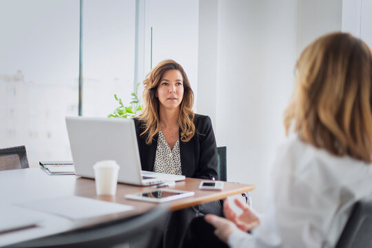 Two professional women collaborating on a project in office