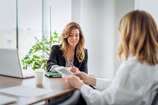 Two professional women collaborating on a project in office