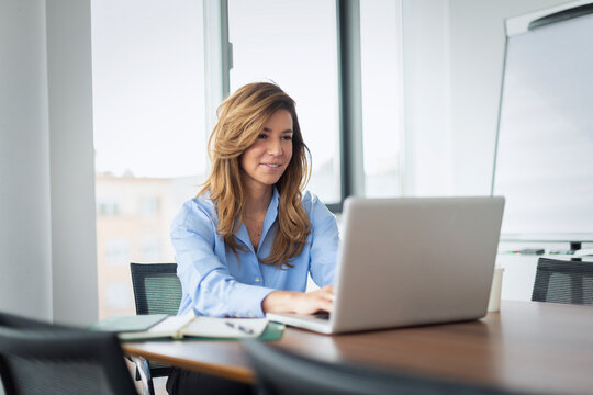 Confident middle-aged businesswoman using her laptop in a modern office
