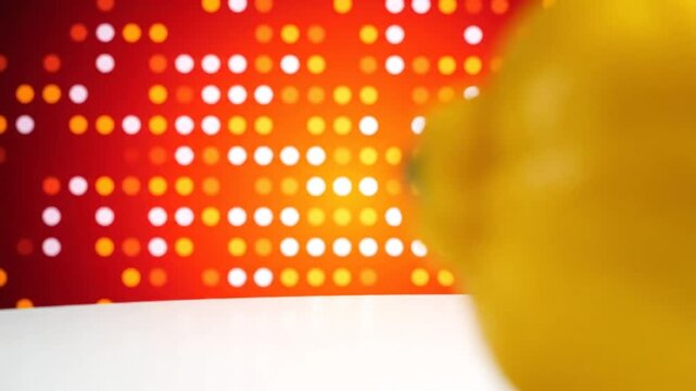 Brightly lit single lemon fruit on a clean white surface with a geometric color background