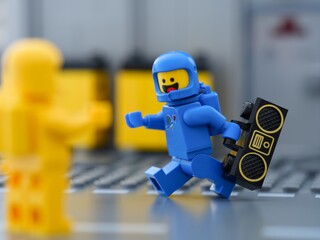 Fototapeta premium Tambov, Russian Federation - May 30, 2025 A cheerful blue Lego astronaut minifigure running with a boombox towards a yellow companion.