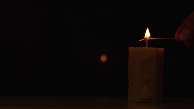 Lighting a Natural Beeswax Honeycomb Candle with a Wooden Match on a Dark Background with Copy Space
