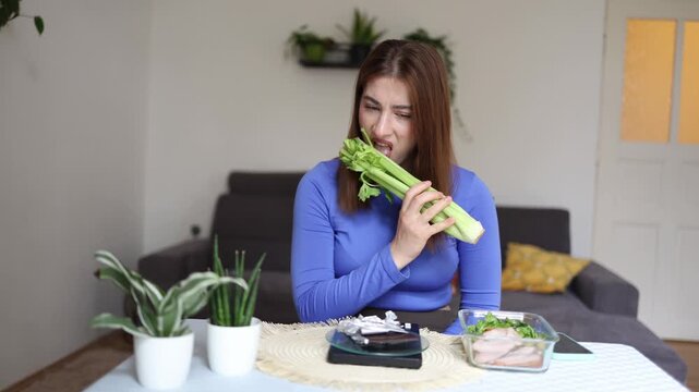 Young woman forces herself to eat celery while counting calories showing how strict dieting and weight loss goals can make healthy eating feel like a daily struggle